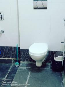 a bathroom with a toilet and a toilet brush at RASA - The Ganges Rishikesh, Ganga Bhumi Apartment in Rishīkesh