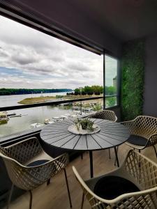 een tafel en stoelen op een balkon met uitzicht op het water bij Goreta032 Luxury Apartment 2 in Vukovar