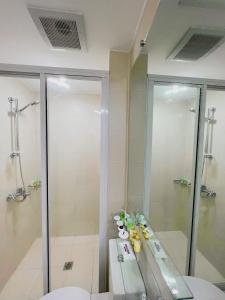 een badkamer met een douche, een wastafel en een spiegel bij Azure North Residences by ACC in Lagundi