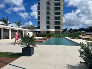 a woman walking past a building with a swimming pool at Luxury Oceanview 1BR on beach in Cupecoy