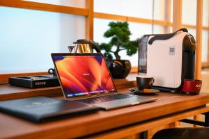 um computador portátil sentado numa mesa ao lado de uma torradeira em Hanami Design Hotel em Belgrado