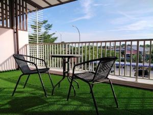un patio con 2 sillas y una mesa en el balcón en No 68 Sunlight Homestay 4R3B - 24 Pax, Karaoke en Kuala Selangor