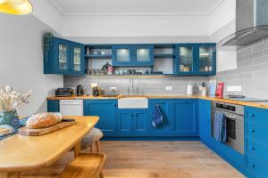 a blue kitchen with a wooden table and blue cabinets at Beeswing, a Victorian Gem in Biggar in Biggar