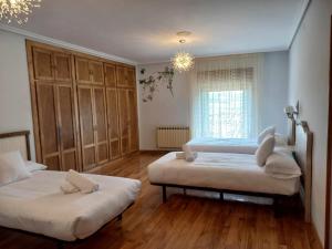 1 dormitorio con 2 camas y lámpara de araña en Casa Albaitar Jardin privado exclusivo clientes en Azcona