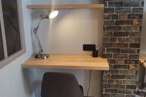 einen Schreibtisch mit einer Lampe neben einer Ziegelwand in der Unterkunft Appartement tout équipé proche gare et centre in Dijon