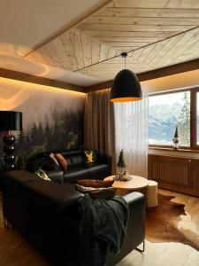 a living room with a black couch and a table at Apartament SMRECEK na Pająkówce in Kościelisko