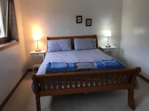 een slaapkamer met een bed met blauwe kussens en 2 lampen bij Heron’s View in Arrochar