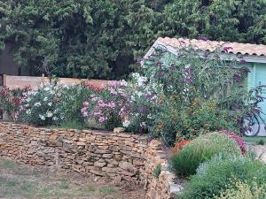 einen Garten mit Blumen und einer Steinmauer in der Unterkunft "Le Colibri" dans la colline in La Ciotat