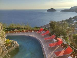 piscina con sedie a sdraio e oceano di Hotel Villa al Mare a Ischia
