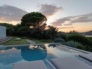 a swimming pool with a sunset in the background at Summer Villa in Porto Rafti in Porto Rafti
