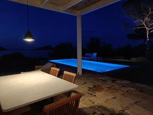 una mesa y sillas en un patio por la noche en Summer Villa in Porto Rafti, en Porto Rafti