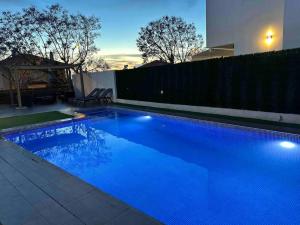 una piscina azul en un patio trasero por la noche en Modern 5-bedroom villa with pool, en Montequinto