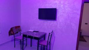 Dieses lila Zimmer verfügt über einen Tisch, Stühle und einen TV. in der Unterkunft RESIDANCE ESSALAM in El Aaiún