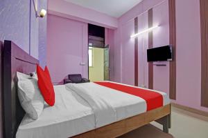 a bedroom with pink walls and a bed with red pillows at Super OYO Flagship Hotel Glorious Stayz in Noida