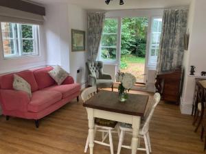 a living room with a red couch and a table at Cosy Cottage in Sawbridgeworth