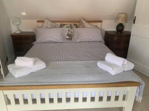 a large white bed with two towels on it at Cosy Cottage in Sawbridgeworth