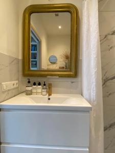 a bathroom with a white sink with a gold mirror at Vondelpark Suite in Amsterdam