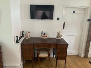 a wooden desk with a chair and a television on a wall at Cosy Cottage in Sawbridgeworth