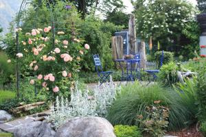 einen Garten mit rosa Blumen, einem Tisch und Stühlen in der Unterkunft Wohnen am See Villa Schrötter direkt am Traunsee in Rindbach