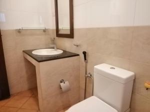 a bathroom with a white toilet and a sink at Golden Residence in Anuradhapura