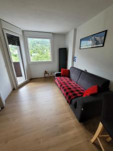 a living room with a black couch and two windows at Chamonix sud -Le Grepon in Chamonix-Mont-Blanc