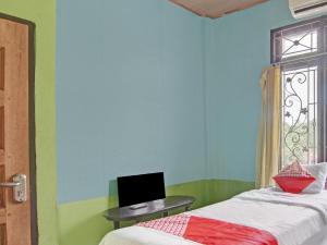 Schlafzimmer mit einem Bett, einem Schreibtisch und einem Fenster in der Unterkunft OYO 92872 Swakarya Guest House in Parit