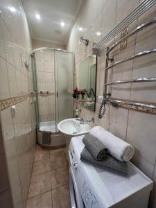 Un baño blanco con lavabo y ducha. en Cozy apartment near the Lviv National Opera, en Leópolis