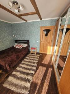 1 dormitorio con cama y alfombra en el suelo en Sadyba Sunny House, en Pilipets