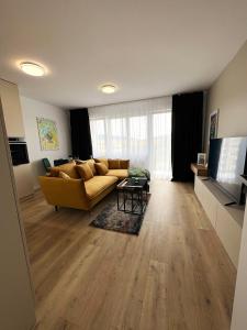 uma sala de estar com um sofá amarelo e uma televisão em Cozy Stay Apartment em Trenčín