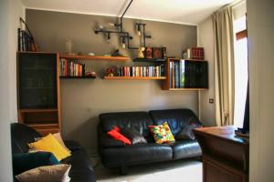 ein Wohnzimmer mit einem schwarzen Ledersofa und Bücherregalen in der Unterkunft Casa de Chicca - Cute Apartment near Lake Nemi in Genzano di Roma