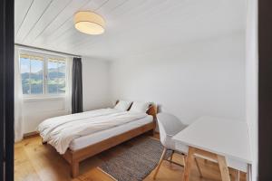 um quarto com uma cama, uma mesa e uma janela em Casa Tschuetta, Cadruvi 4, 7159 Andiast em Andest
