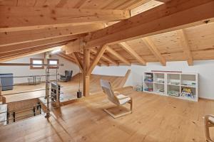 um quarto com tectos em madeira, uma cadeira e uma secretária em Casa Tschuetta, Cadruvi 4, 7159 Andiast em Andest
