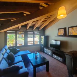 a living room with a blue couch and a tv at vivienda rural AZALEA in Cortijos Nuevos
