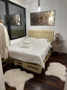 a bedroom with a bed with white sheets and two rugs at Casuta Nest in Curtea de Argeş