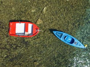 een rode boot en een blauwe kajak op het water bij Elena's Seafront Deluxe Studios in Zakynthos