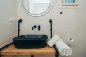 ein Bad mit einem schwarzen Waschbecken und einem Spiegel in der Unterkunft Loukoum House in Kástron