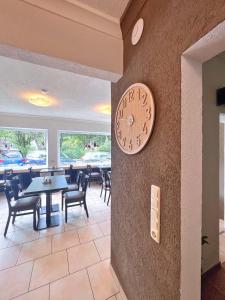 un reloj en la pared de un restaurante con mesas y sillas en Hotel Frohnhauser Hof, en Essen