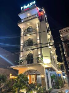 um edifício alto e branco com um letreiro de néon. em HÀ ANH hotel em Phường Sáu