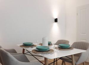 a white table with four chairs and blue bowls on it at Cozy, Quiet Munich City Apartment in Munich