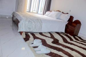 a bedroom with a bed with shoes on a rug at Green Safaris Apartment in Rubavu