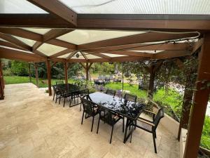 eine Terrasse mit Tischen und Stühlen unter einem Pavillon in der Unterkunft La clé des champs - Les Grais 1H10 de Paris in Bazoches-sur-le-Betz