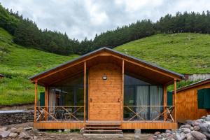 una cabaña de madera con una colina de césped en el fondo en Gergeti Trio en Kazbegi