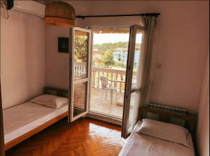 a room with two beds and a door to a balcony at Peaceful, Cosy Tivat Guesthouse in Tivat