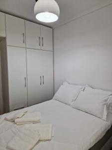 uma cama branca com armários brancos e toalhas em Valentina's Apartment em Olympiada
