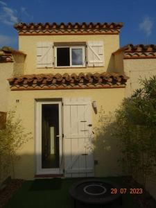 ein Haus mit einer weißen Tür und einem Fenster in der Unterkunft Baby Home cosy à 1km de la mer in Saint-Cyprien