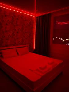 Cette chambre rouge comprend un lit et une fenêtre. dans l'établissement Двухкомнатная квартира, à Aksay