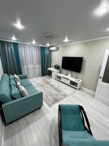 Il comprend un salon doté d'un canapé et d'une télévision à écran plat. dans l'établissement Двухкомнатная квартира, à Aksay