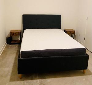 a black bed in a room with two tables at Downtown Near Busch Stadium/Convention Center in Saint Louis
