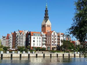 een groot gebouw met een klokkentoren naast een rivier bij Apartament Amber Dwie Sypialnie Stare Miasto in Elblag