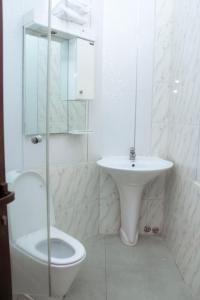 a white bathroom with a toilet and a sink at Résidence Vedette in Yaoundé